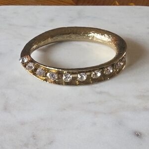 gold-tone hinged bangle bracelet with a textured finish and clear crystals. 